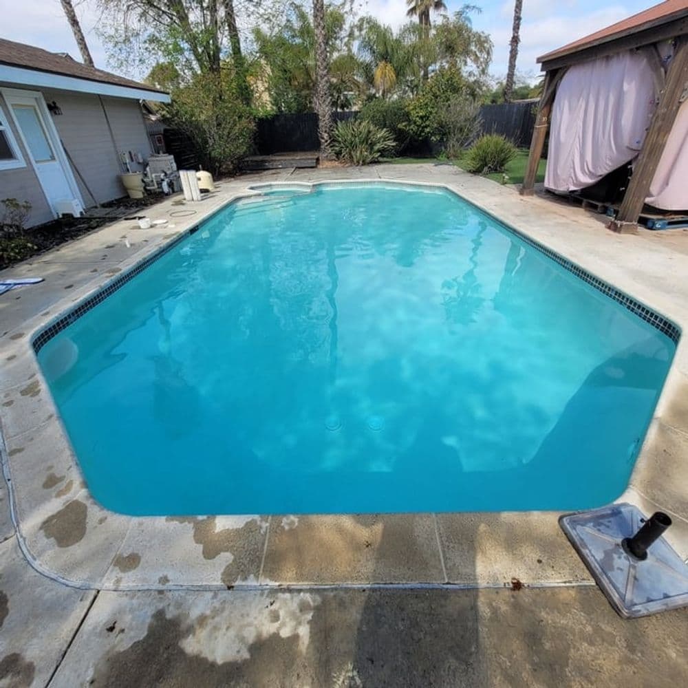 Crystal clear swimming pool surrounded by palm trees and patio area. Ideal for relaxation.
